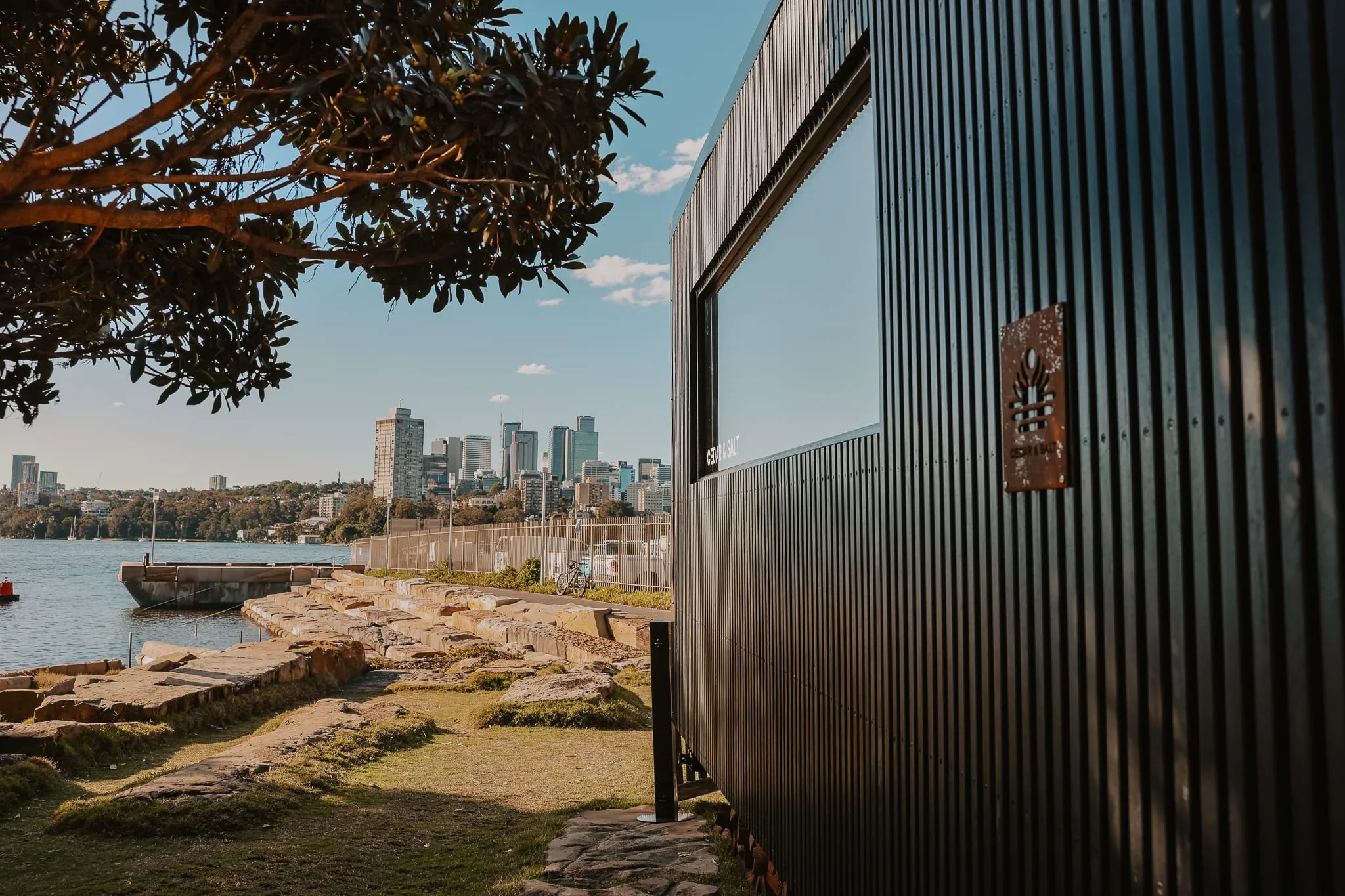 A wood-fired mobile sauna on a headland with the Sydney skyline across the water